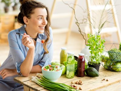 Frau in heller Küche beim Essen einer veganen Salat Bowl