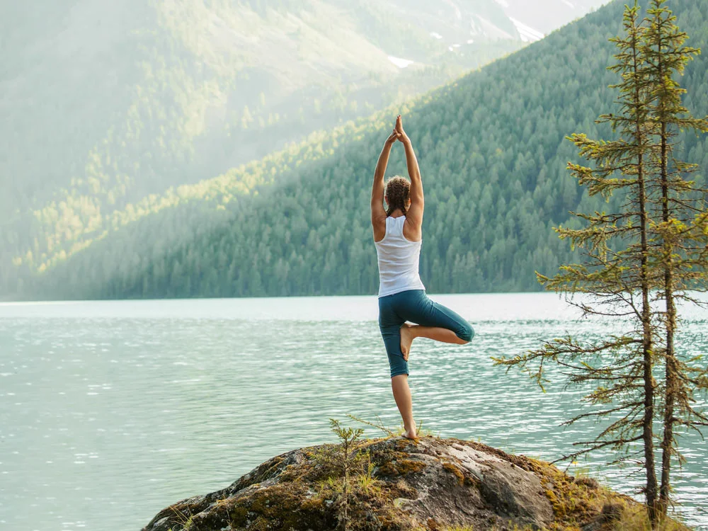 Frau in Yoga-Baumhaltung am Bergsee – fit und gesund mit ausreichend Eisen